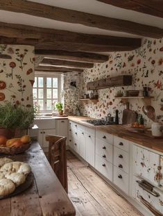 an old fashioned kitchen with wooden floors and white cabinets, decorated in floral wallpaper