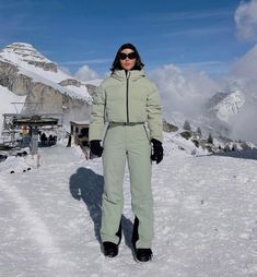 a woman standing on top of a snow covered slope wearing skis and goggles