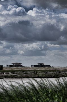 the sky is filled with clouds and there are some buildings in the distance on the other side