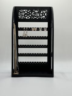 a black and white display case with jewelry on it's sides, in front of a gray background