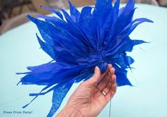 a hand holding a blue flower on top of a table