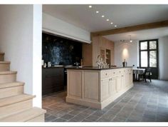 a kitchen and dining room with stairs leading up to it