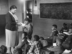 a woman standing in front of a classroom full of children