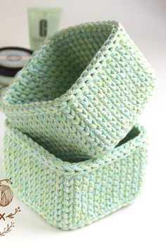 a green knitted basket sitting on top of a white table next to a cup