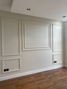 an empty room with white paneling and wood floors in the center is painted off