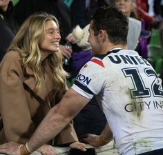 a man and woman sitting next to each other on a bench in front of a crowd