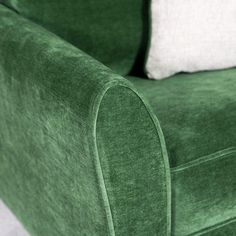 a green couch with two white pillows on it's back and the seat upholstered