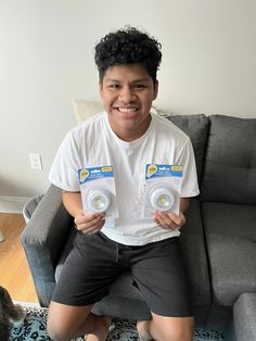 a man sitting on top of a couch holding up two small white frisbees