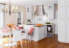 a kitchen filled with lots of white furniture and decor on top of a hard wood floor