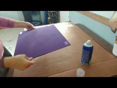 a woman is making a purple piece of paper on a table with glue and paint