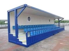 an empty blue and white baseball dugout with stairs leading up to the top level