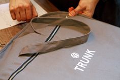 a person holding onto a gray bag on top of a wooden table