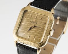 "Movement #320 Case #182124 18k Yellow Gold Textured Square Case 29 mm Wide 29 mm Long Lug-to-Lug Distance = 38 mm Lug-to-Lug Width = 19 mm Thickness = 7 mm Gold Dial w/ Gold Hands (M + H) and Tic Marks 23 mm Wide 23 mm Long Black Leather Aftermarket Band w/ Gold-Plated Clasp Total Length = 8.5\" Largest Wrist Fit = 7.75\" Total Mass = 27.8 grams Does Not Include Original Box or Papers This watch is guaranteed authentic. One year warranty included with purchase." Kara Kara, Gold Hands, Gold Texture, Wristwatch Men, Leather Band, Cool Watches, Vintage Watches, Time Piece, Wrist Watch