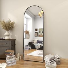 a large mirror sitting on top of a wooden floor next to a dresser and table