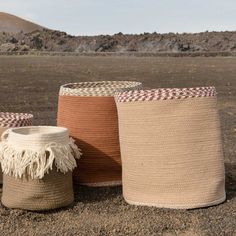 three woven baskets sitting on top of a dirt field