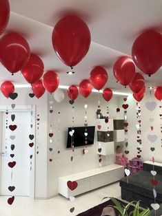 red and white balloons are hanging from the ceiling in a room decorated with heart - shaped confetti