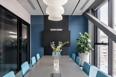 a long table with blue chairs is in the middle of an office meeting room area