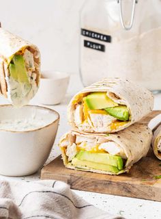 a burrito cut in half with avocado and cheese on the wrapper