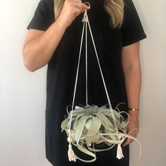 a woman is holding a plant in front of her face while wearing a black shirt