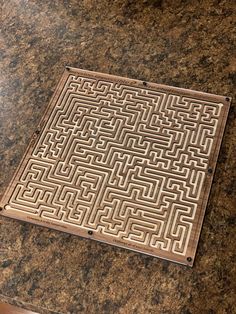 a brown tile with an intricate design on it sitting on a counter top next to a cup