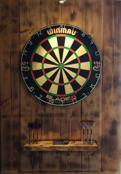 a dart board mounted to the side of a wooden wall with darts in front of it