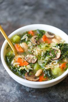 a white bowl filled with chicken soup on top of a table next to a spoon