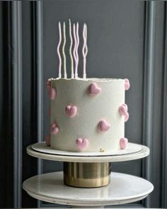 a white cake with pink hearts on it and candles in the shape of heart's