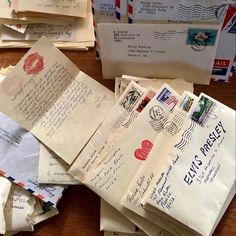 many envelopes are piled on top of each other with letters and stamps all over them