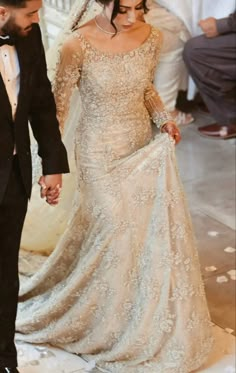 a man and woman in formal wear walking down the aisle at their wedding ceremony, holding hands