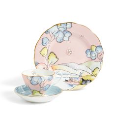 two tea cups and saucers with flowers on the side, one is pink and blue