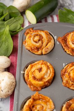 some food is in a muffin tin on a table next to vegetables and leaves