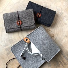 three felt cases sitting on top of a wooden table next to an ipod charger