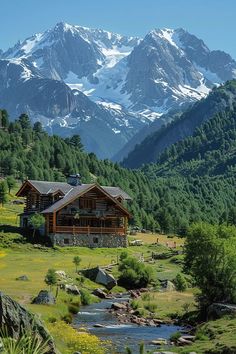 a house in the mountains with a stream running between it and snow capped mountains behind