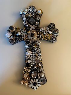 a cross made out of buttons and other items on a white surface with a light brown background