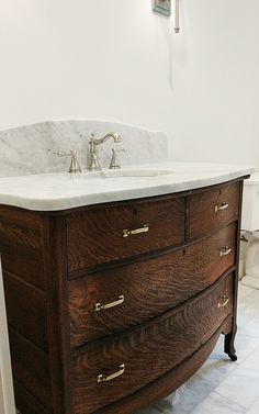 a bathroom vanity with marble top and wooden drawers