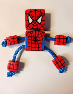 a spider man made out of legos on a white surface with blue cords and eyes