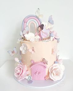 there is a pink cake decorated with flowers and fairy figurines