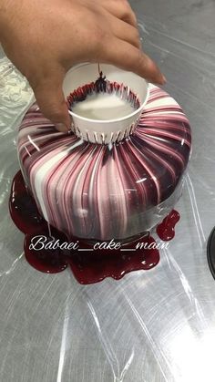 someone is decorating a cake with red and white icing