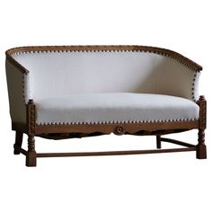 a white couch sitting on top of a wooden frame with studded trimmings