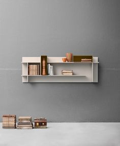 a white shelf with books and vases on it next to two stacks of books