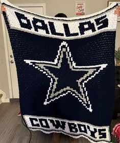 a man is holding up a blanket with the word dallas written in white on it