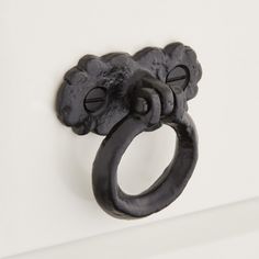 an old black door handle on a white wall with two knobs in the shape of flowers