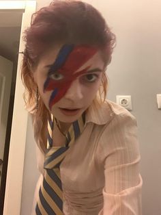 a woman with red hair wearing a striped tie and clown face painted on her shirt