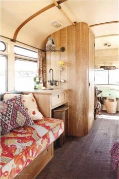 the inside of a motor home with wood paneling and colorful pillows on the couch