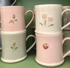 four coffee mugs with flowers and hearts on them are stacked next to each other