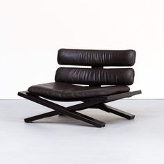 a black leather chair sitting on top of a metal frame with an x - base