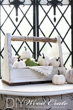 white pumpkins and gourds in a wooden crate on a table with black ironwork