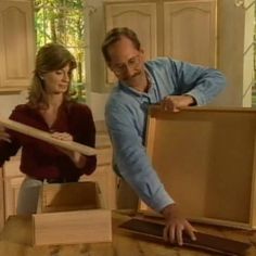 a man and woman moving boxes in the kitchen