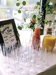 there are many glasses on the table with some drinks in front of them and a sign