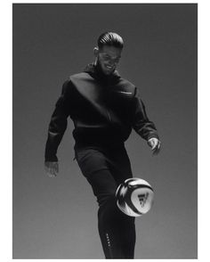 a black and white photo of a man kicking a soccer ball with his right foot